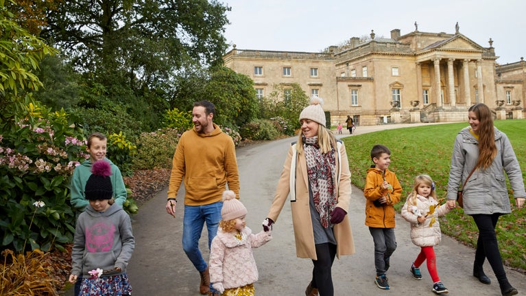 Adults and children wrapped up warm walk down a track away from the house at Stourhead